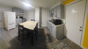 A compact kitchen with a dining table, chairs, a refrigerator, a stove, and a microwave. - Perfect 3-bedroom apartment  in  Waterbury CT (Waterbury)