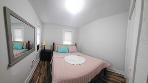 A bedroom with a bed, a nightstand, a lamp, a mirror, and a window. - Perfect 3-bedroom apartment  in  Waterbury CT (Waterbury)