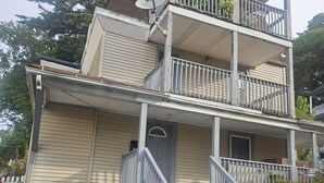 A two-story building with a balcony on the upper floor, a satellite dish, and a car parked in front. - Perfect 3-bedroom apartment  in  Waterbury CT (Waterbury)