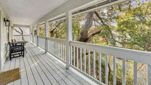 A covered porch with white railings and a table with chairs. - Amelia Island 3 Bedroom Sea Escape (Fernandina Beach)