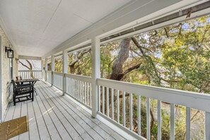 A covered porch with white railings and a table with chairs. - Amelia Island 3 Bedroom Sea Escape (Fernandina Beach)