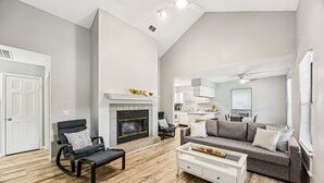A spacious living room with a fireplace, a sofa, a coffee table, and a chair. - Amelia Island 3 Bedroom Sea Escape (Fernandina Beach)