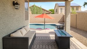 A covered patio with a pool, outdoor furniture, and a solar panel on a house. - Charming 3-bedroom Luxury Home, Perfect for Entertaining (Waddell)