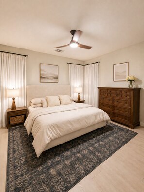 A bedroom with a bed, nightstands, a dresser, a ceiling fan, and two framed pictures on the wall. - Charming 3-bedroom Luxury Home, Perfect for Entertaining (Waddell)