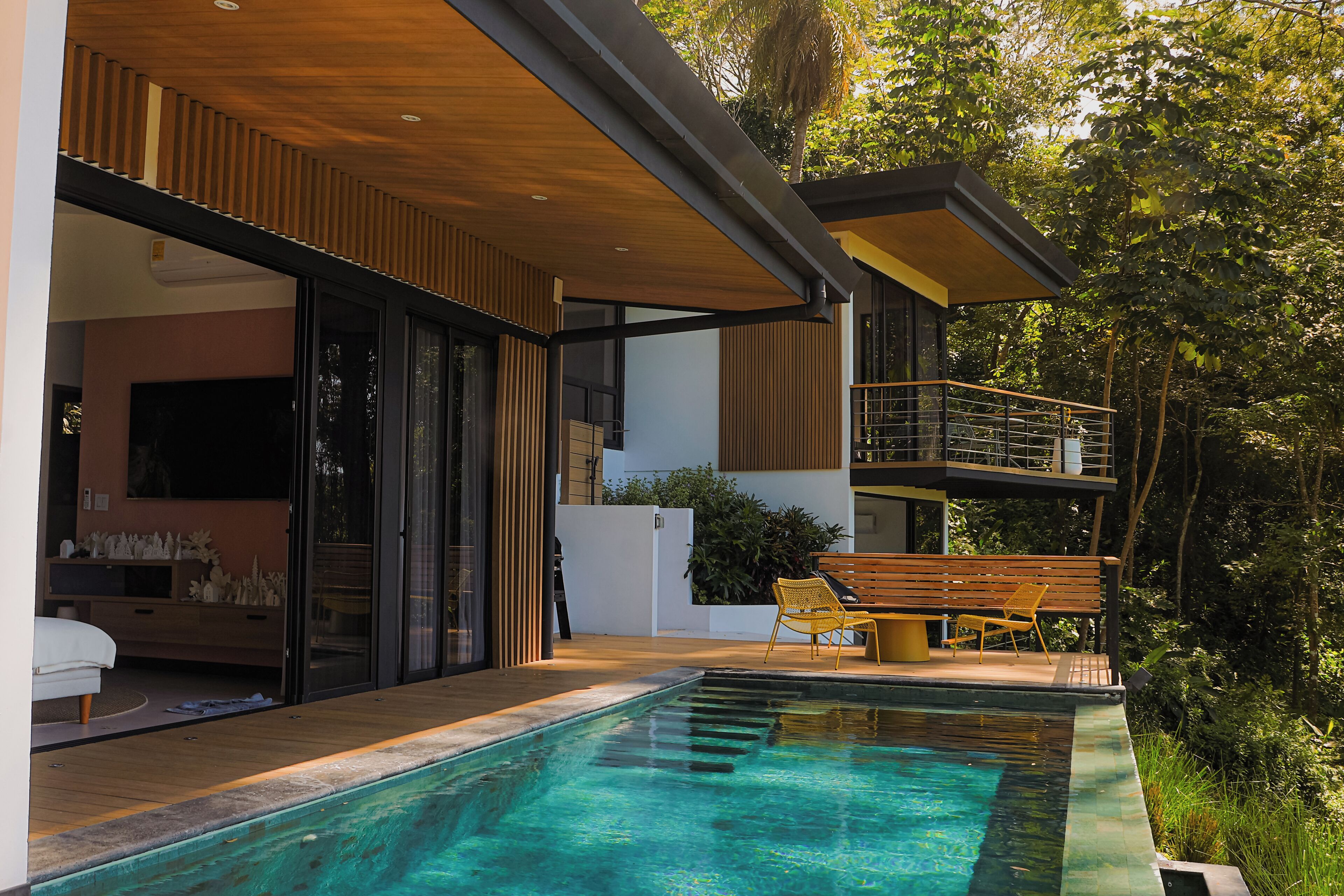 Une maison moderne dotée d’une piscine, d’une terrasse en bois et d’un balcon donnant sur le jardin.