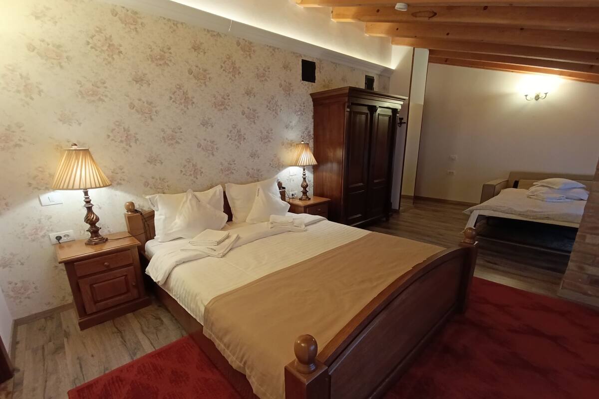 A bedroom with a wooden bed, two bedside tables with lamps, a wardrobe, and a red rug.