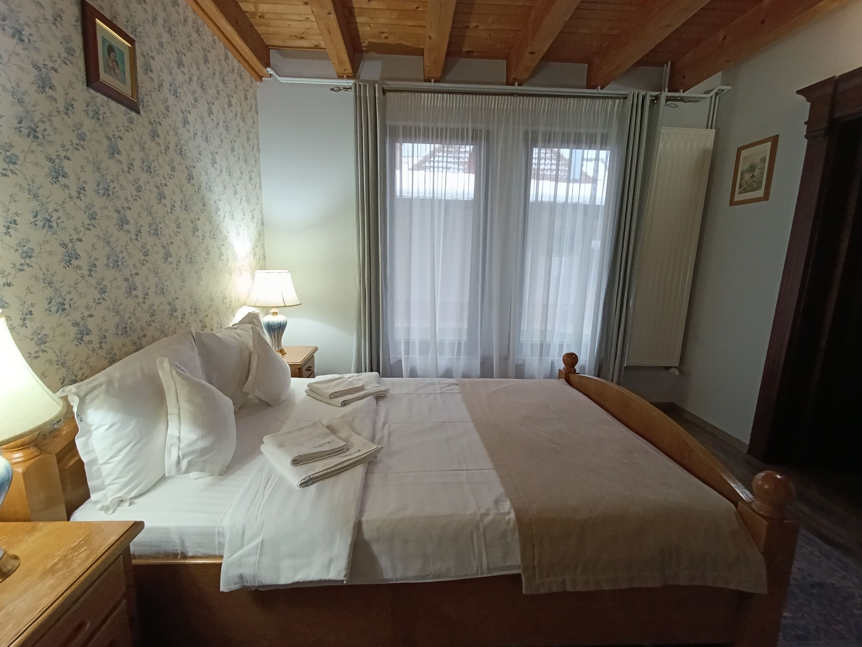 A neatly made bed with white linens, a wooden headboard, and a bedside table with a lamp.