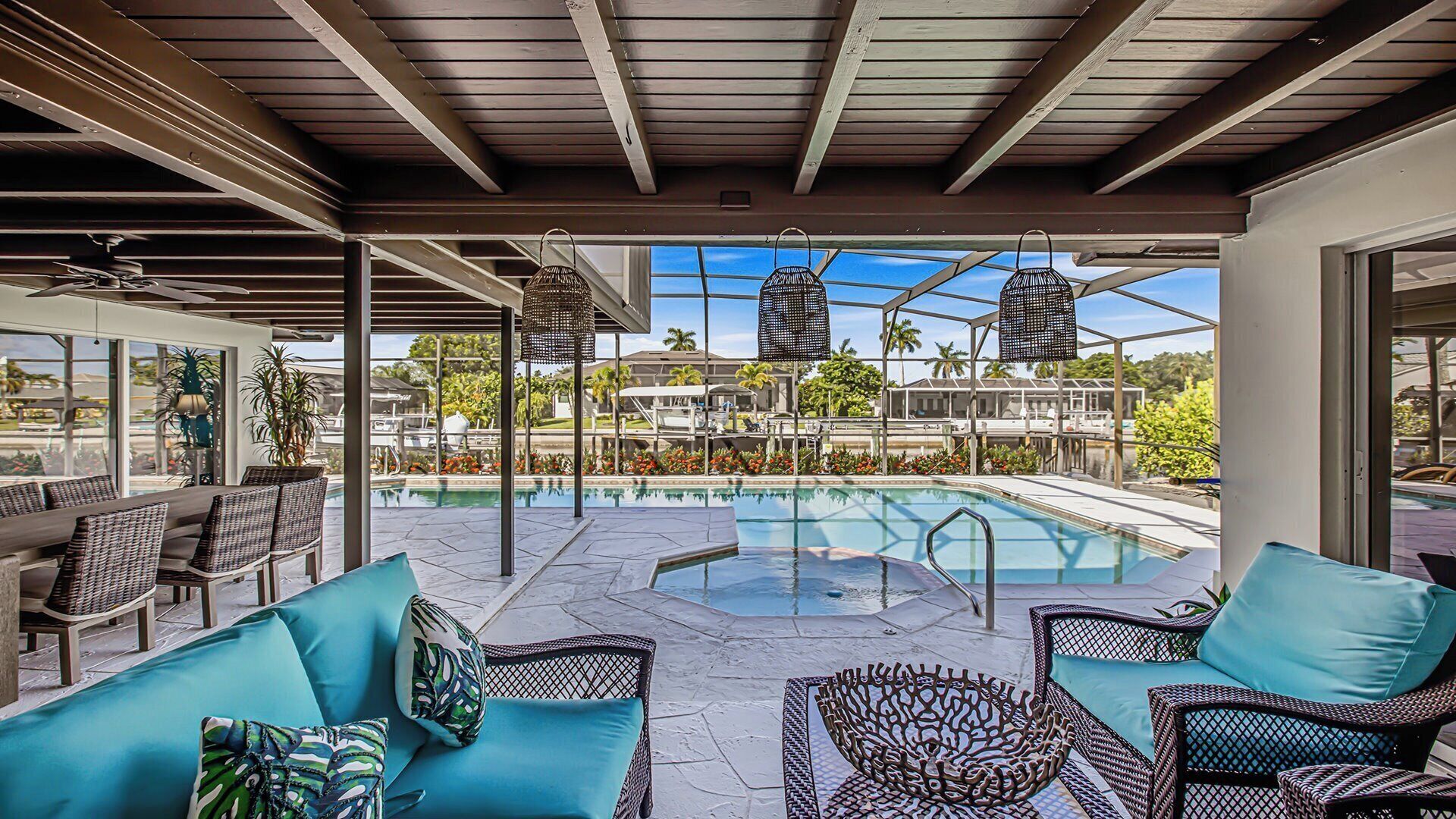 A covered outdoor area with a pool, lounge chairs, and a view of the surrounding landscape.