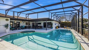 A pool with a glass enclosure, outdoor seating, and a covered patio area. - Indulge in your Marco Island Haven. (Marco Island)