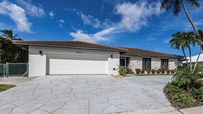 Einbungalow mit Garage, Natursteinhausfassade und befestigter Auffahrt.