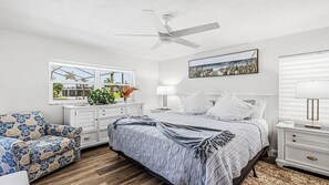 A bedroom with a bed, a chair, a nightstand, a lamp, a ceiling fan, and a window with a view. - Indulge in your Marco Island Haven. (Marco Island)
