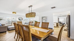 A modern dining area with a wooden table, wicker chairs, and a hanging light fixture. - Indulge in your Marco Island Haven. (Marco Island)