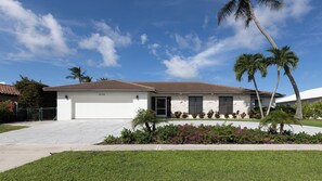 A single-story house with a garage, number 828, surrounded by a well-maintained lawn and palm trees. - Indulge in your Marco Island Haven. (Marco Island)