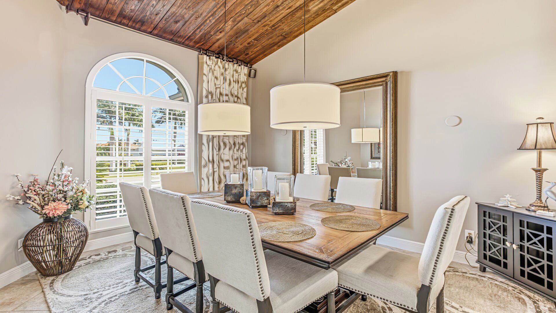 A dining area with a wooden table, chairs, and a large mirror.