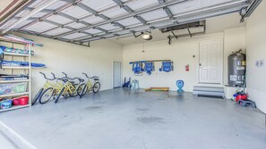 Eine Garage mit Fahrrädern, Regalen mit Aufbewahrungsbehältern, einem Warmwasserbereiter und einem Feuerlöscher.