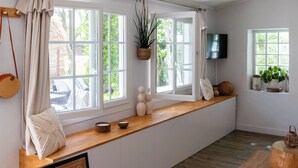 Une cuisine avec un plan de travail en bois, des armoires blanches et de grandes fenêtres.