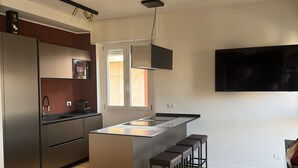 Et moderne køkken med en central ø, rustfrit stål-hvidevarer og et stort vindue.