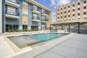 A modern apartment building with a pool area, including a lounge and a covered seating area.