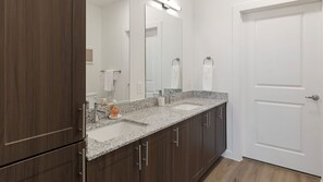 A bathroom with a double sink, dark wood cabinets, a large mirror, and a white door.