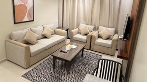 A living room with two sofas, a coffee table, and a striped chair. - Nozol Aram 4 Elnafal (Riyadh)