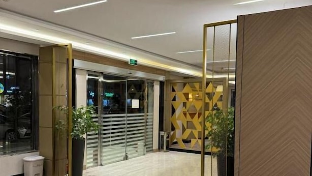 A modern lobby with a herringbone floor pattern, a glass entrance, and a decorative wall with geometric patterns. - Nozol Aram 4 Elnafal (Riyadh)
