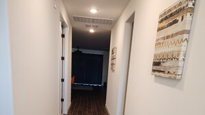 A hallway with brown tiled flooring, white walls, and a ceiling light. - Casa Limpia Tucson! (Tucson)