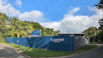 A blue wall with 'EL CARDUMEN RESTAURANT' signage, a clear sky, and a road curving to the right.