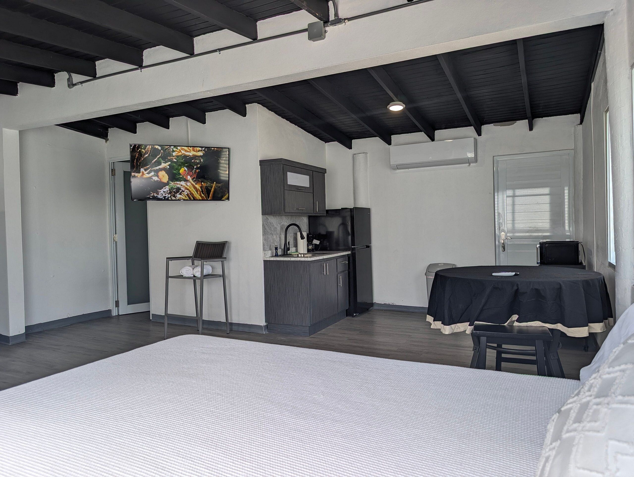 A modern room with a bed, a small kitchenette, a dining table, and a TV.