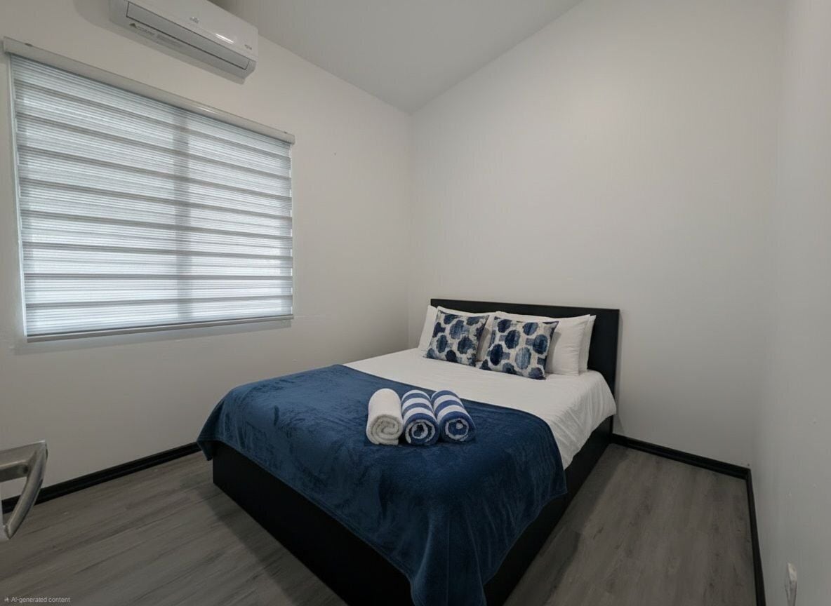A bedroom with a bed, a window with blinds, a chair, and a wall-mounted air conditioner.
