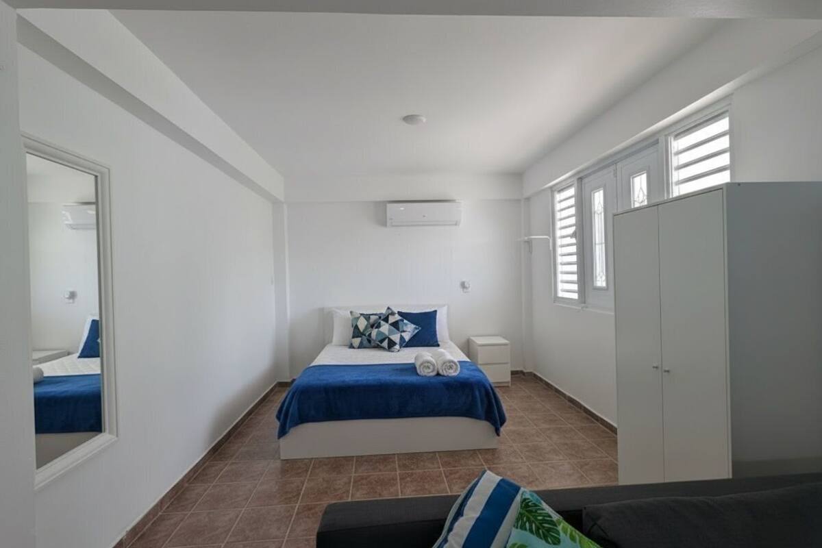 A bedroom with a bed, a wardrobe, a nightstand, and a mirror.