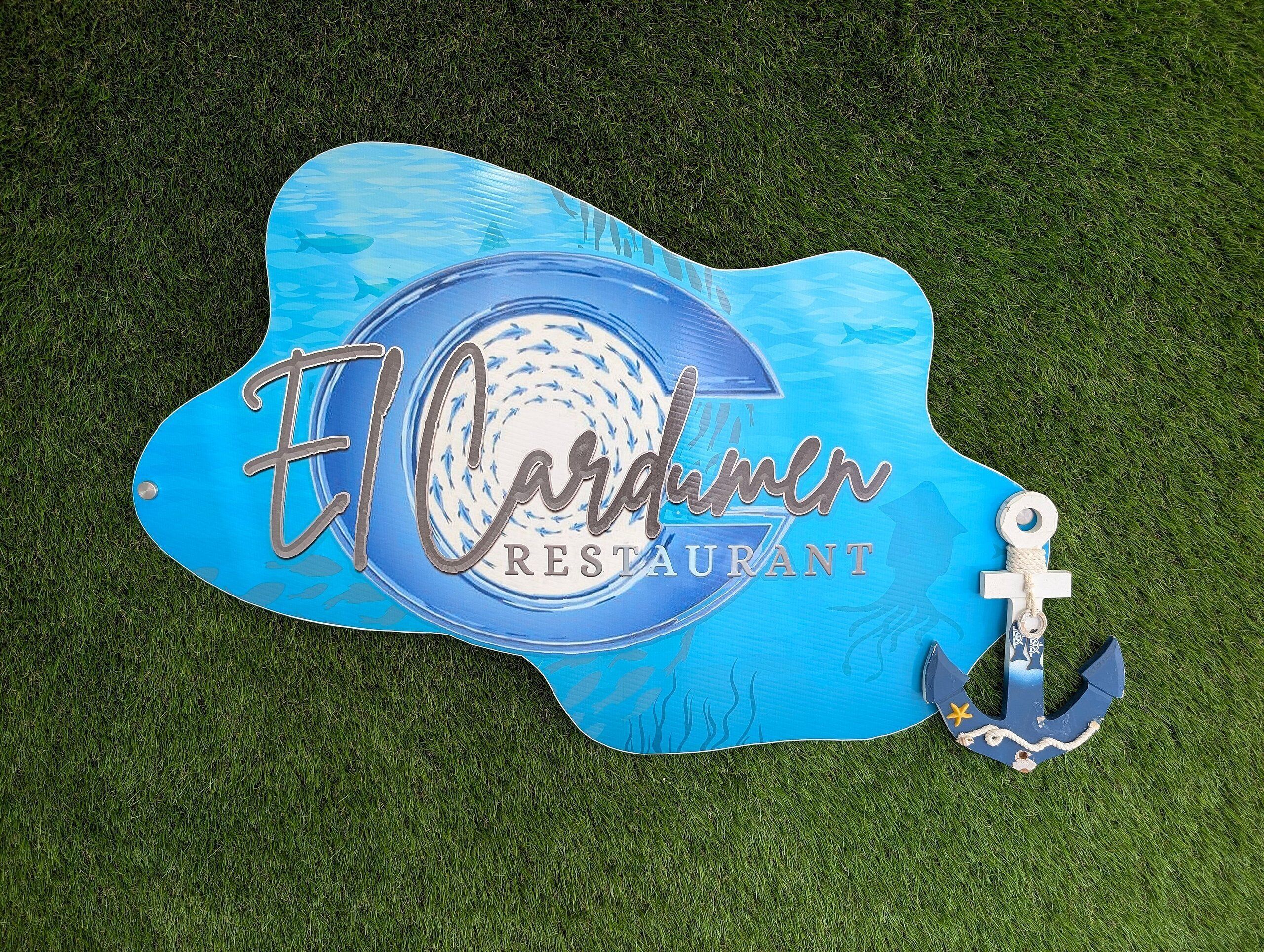 Un panneau bleu avec l’inscription « Restaurant El Cardenal » et un symbole d’ancre.