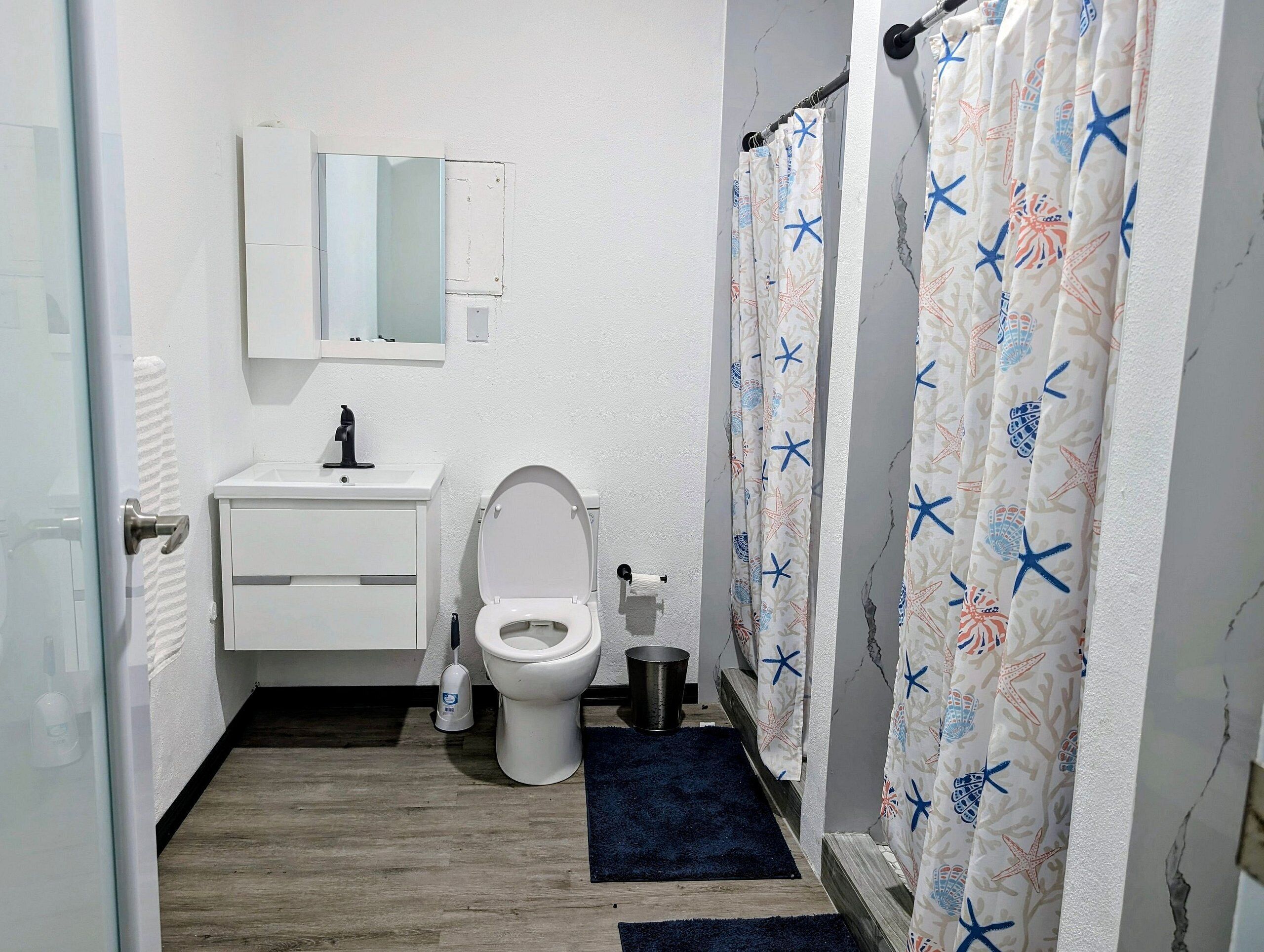 Ein Badezimmer mit Toilette, Waschbecken, Spiegel und Duschvorhang.