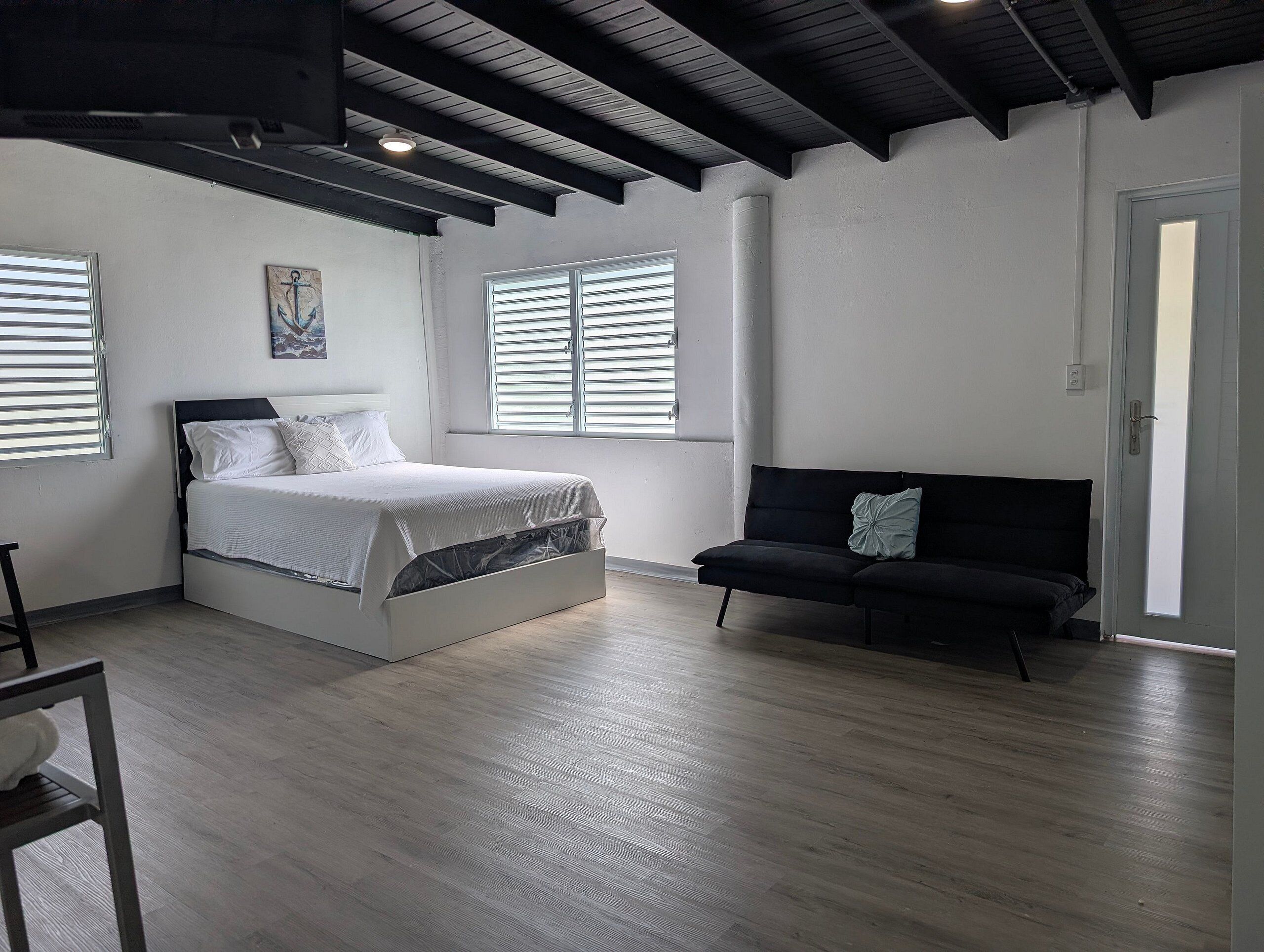 Un dormitorio con una cama, un sofá negro y una ventana.