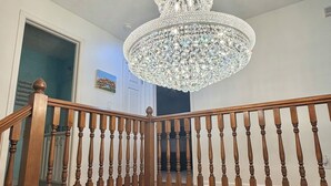 Un escalier en bois surmonté d’un lustre.