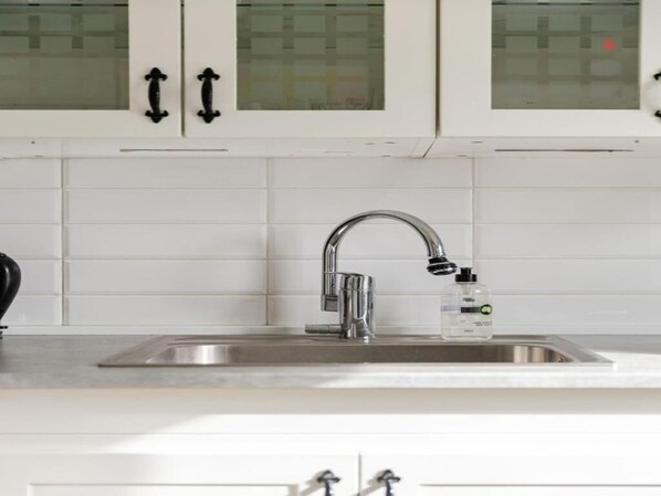 A kitchen with white cabinets, a stainless steel sink, and a faucet. - Charming 2-bedroom Apartment in Rejmyre With Garden View (Rejmyre)