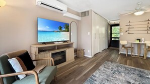 Ein Wohnzimmer mit Fernseher, Kamin, einer Couch und einem Essbereich mit Stühlen.