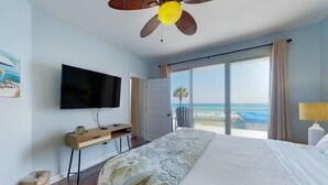 Une chambre avec un lit, une télévision, un bureau et une vue sur la plage.
