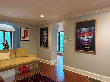 A living room with a sofa, a glass coffee table, and a red bowl. There are two framed posters on the wall and a statue on the left.. STAFFORD ESTATE IN HISTORIC PHILADELPHIA