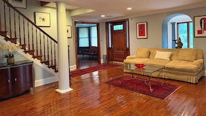 A spacious living room with a wooden staircase, a red rug, a beige sofa, and a statue on a glass coffee table. - STAFFORD ESTATE IN HISTORIC PHILADELPHIA (Philadelphia)
