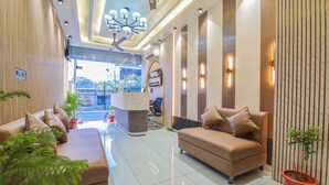 A hotel lobby with a reception desk, two sofas, a chandelier, and potted plants. - Hotel Starlink By The Nine Hotel  (Jaipur)