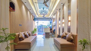 A modern lobby with two sofas, potted plants, a ceiling fan, and a view of the outside. - Hotel Starlink By The Nine Hotel  (Jaipur)