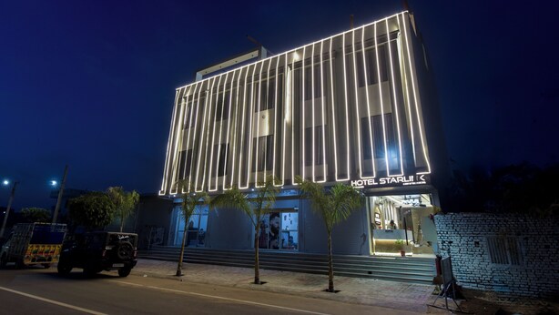 A modern hotel with a prominent vertical light strip design, a visible entrance, and a parked vehicle in front. - Hotel Starlink By The Nine Hotel  (Jaipur)