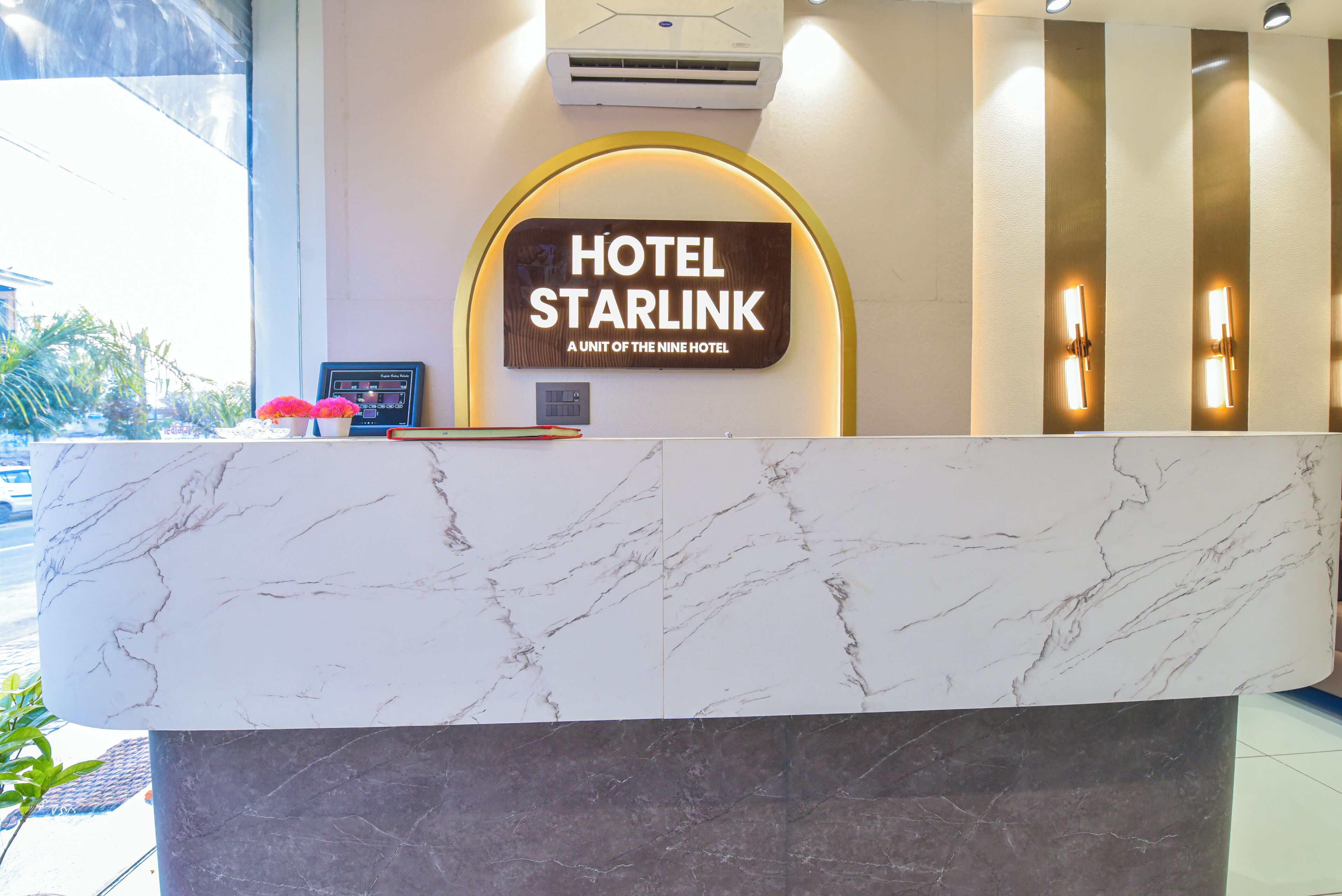 Una reception di hotel con piano in marmo e un cartello che recita 'HOTEL STARLINK A UNIT OF THE NINE HOTEL'.