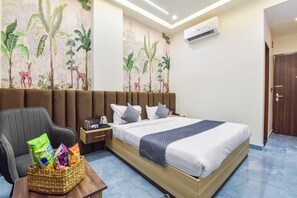 A hotel room with a bed, a chair, a nightstand, and a wall mural. - Hotel Starlink By The Nine Hotel  (Jaipur)