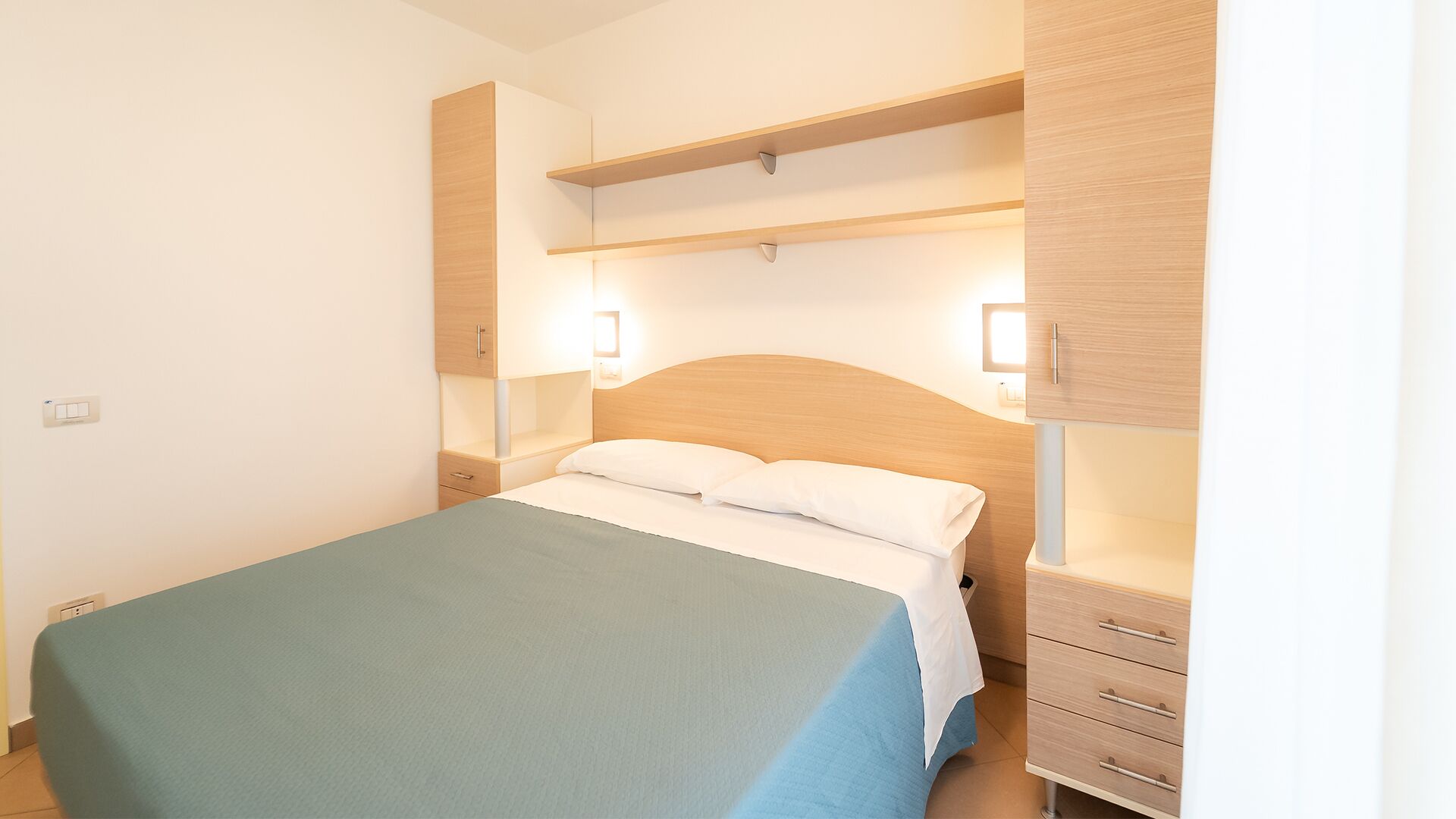 Een slaapkamer met een bed, nachtkastjes, een kledingkast en inbouwverlichting.