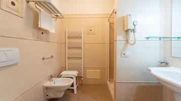 Un baño pequeño con bidé, inodoro y lavamanos.