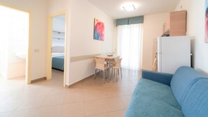 A compact living space with a dining area, a sofa, and a bed. - Anchise Mare Holiday Apartments (Alba Adriatica)