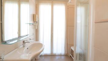 A modern bathroom with a toilet, bidet, and glass shower enclosure.