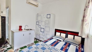 Ein kleines, ordentlich eingerichtetes Schlafzimmer mit Bett, Kleiderschrank und Waschbecken.