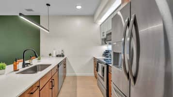 A modern kitchen with stainless steel appliances, wooden cabinets, and a white countertop.